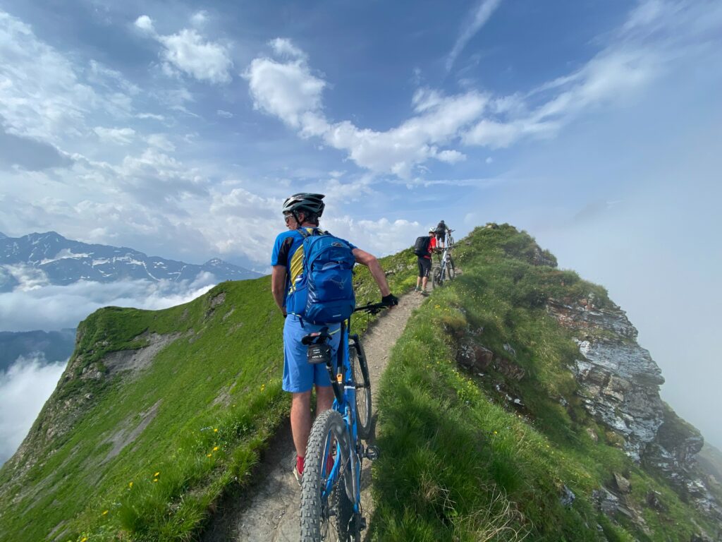 mountain bike riders on a beautiful green ridge trail riding into the cloudy ridge