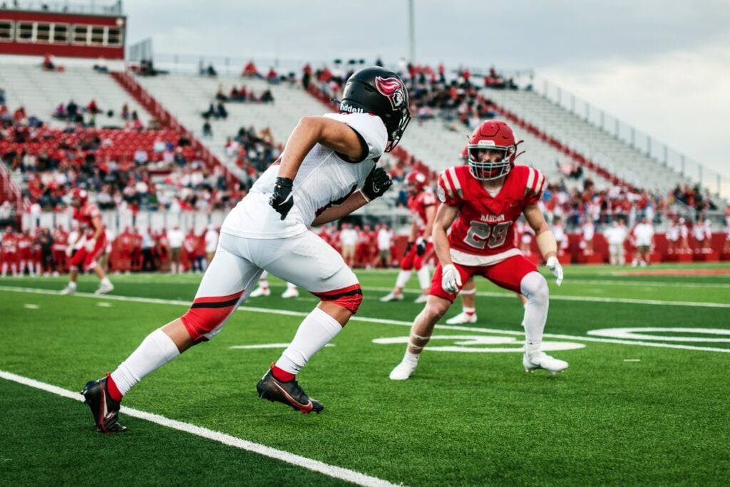 Two men playing American football wearing white and red jerseys