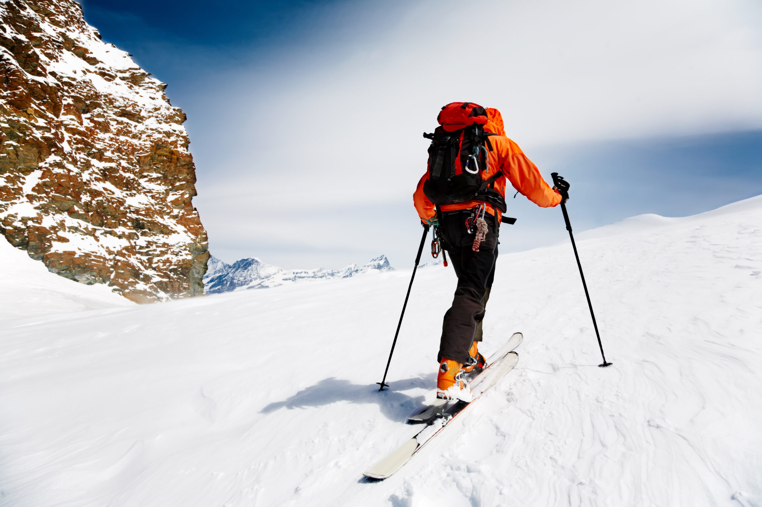 Man climbing on backcountry skis in red coat on a clear day|Portrait of young woman skier in a bright jacket and blue helmet.
