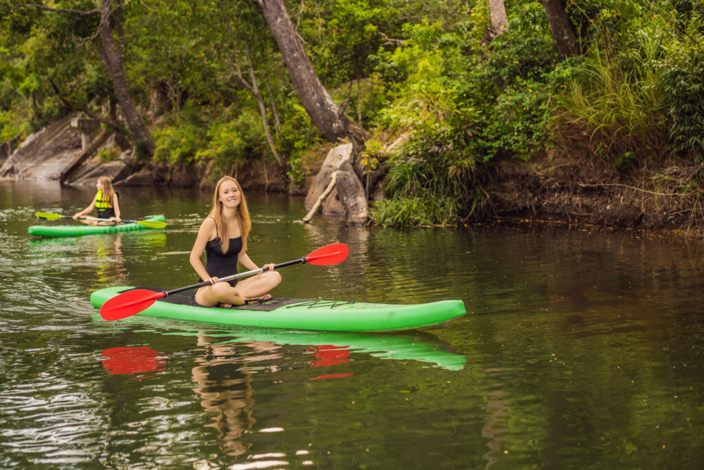 sup stand up paddle board woman paddle boarding on lake standing happy on paddleboard on blue water. action shot of young woman on paddle board|whitewater rafting adventure