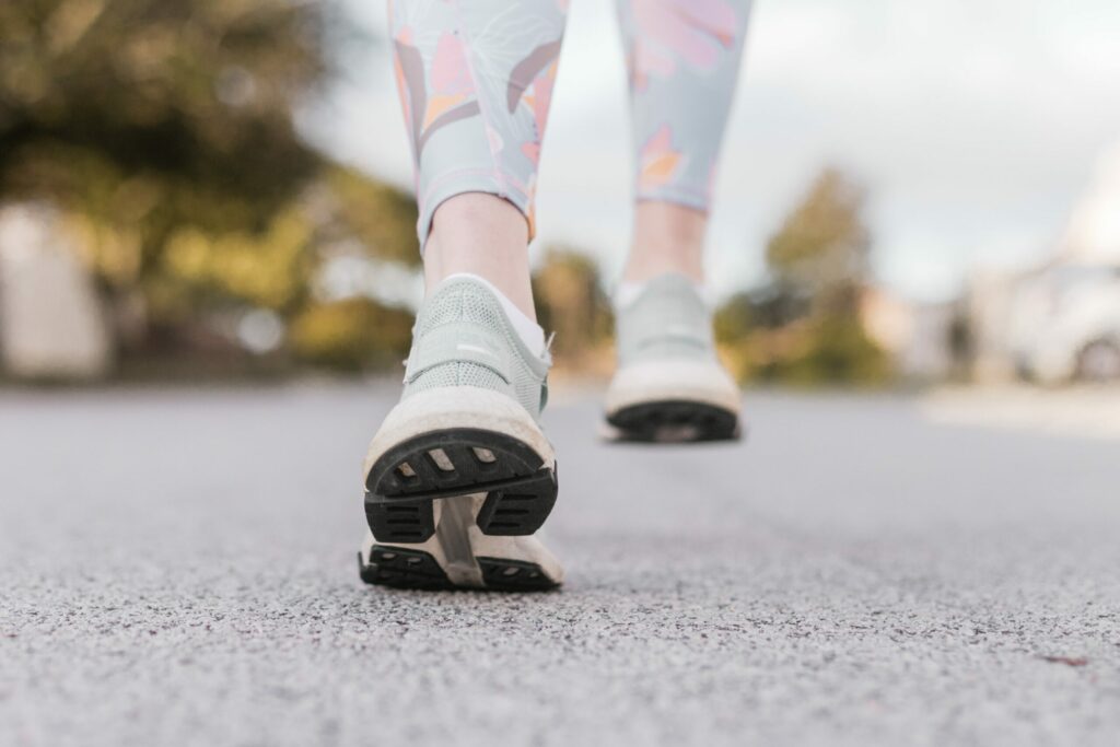 woman walking on pavement in grey shoes|Woman running on the road in the high desert country. Sagebrush and yellow flowers at the forefront.|Grandma and grandchild walking on a forest road.