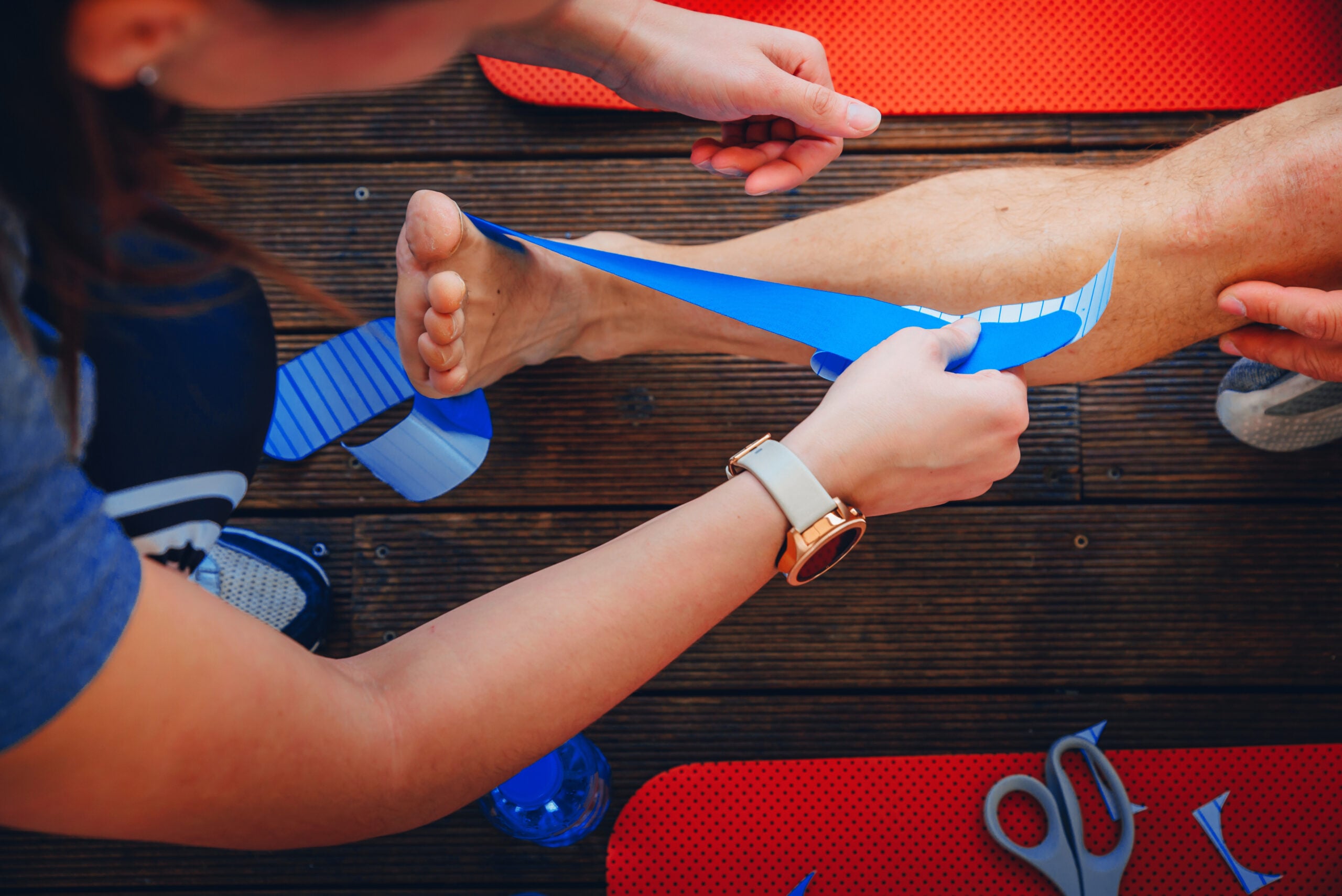 medical taping for leg correction after sport injury|sports medicine doctor helping a patient with recovery exercises|trail runner on single track trail|road runner on paved road with blooming rabbitbrush and sage