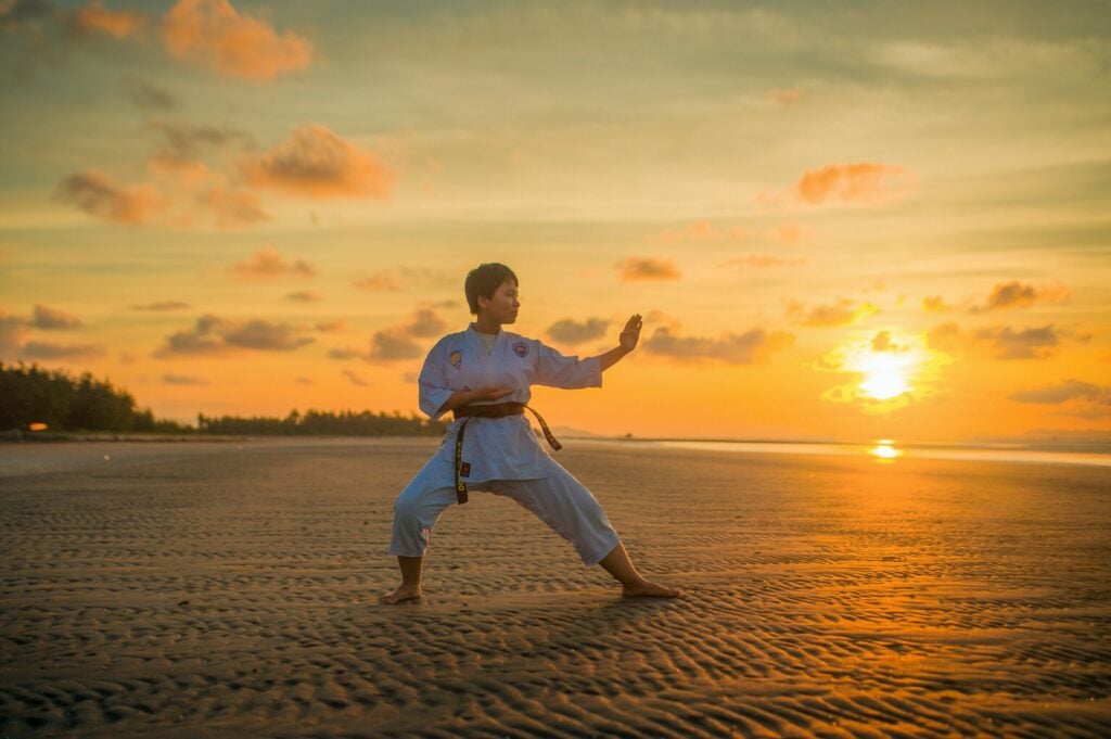 Person on the beach during sunset doing karate|Anatomy diagram showing the medial collateral ligament and an image of a woman with the MCL highlighted.|Two men playing American football wearing white and red jerseys