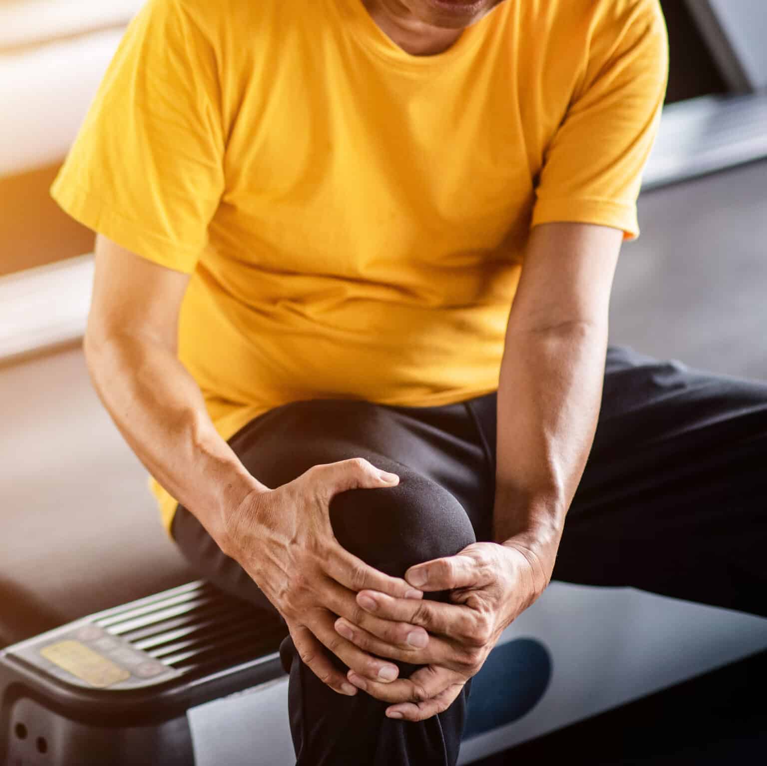 Elderly man having pain in his knee at the gym